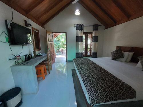 a bedroom with a bed and a television in a room at Inn On The Bay in Pasikuda