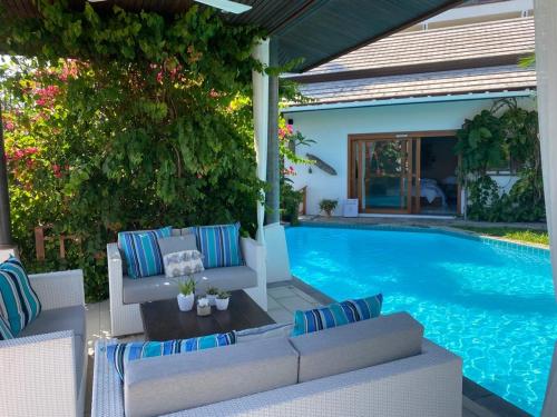 a swimming pool with white furniture next to a swimming pool at Samui Blu, villa with private pool in Choeng Mon Beach