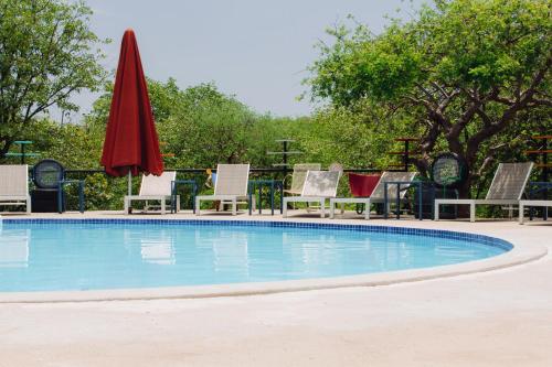 a swimming pool with chairs and a red umbrella at Etosha Safari Camping2Go in Okaukuejo