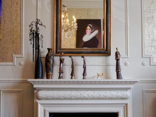 a fireplace in a living room with a portrait of a woman at Le 27- Boutique B&B in Dinan