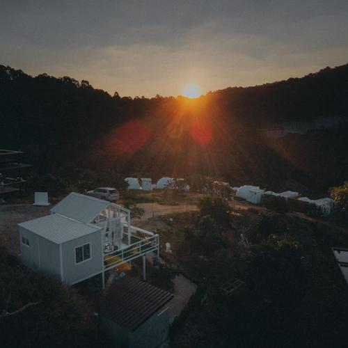 an aerial view of a house with the sunset in the background at Phu Morinn Cafe &Camping Monjam in Mon Jam