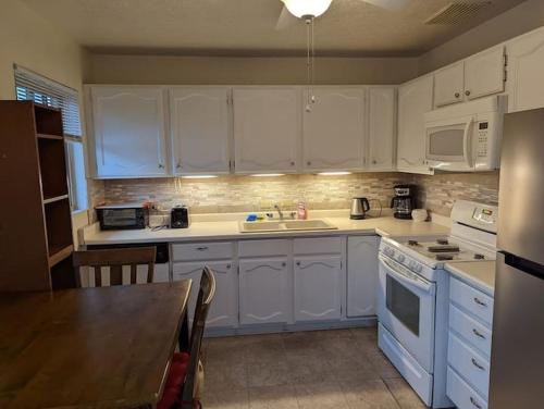 a kitchen with white cabinets and a table in it at Warm and Welcoming 2BR close to UNM North Campus in Albuquerque