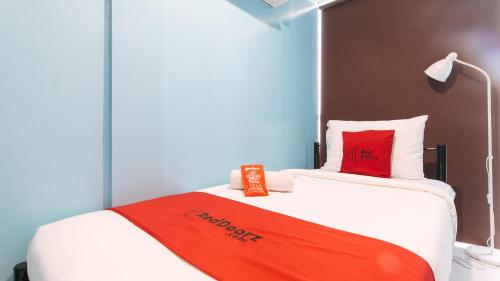 a bedroom with a bed with a red blanket on it at RedDoorz @ Greenview Hotel and Restobar Masbate in Masbate