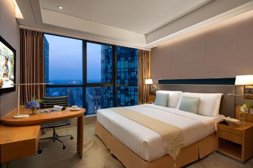 a bedroom with a bed and a desk and a large window at Ascott Raffles City Beijing in Beijing