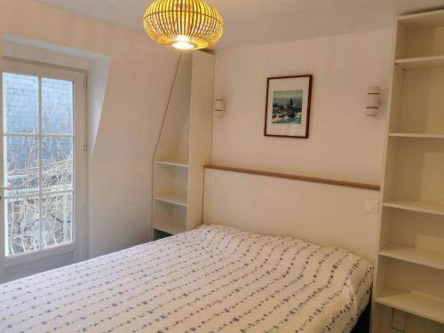 1 dormitorio con cama, estanterías y ventana en La Glycine Hypercentre et tout confort, en Deauville