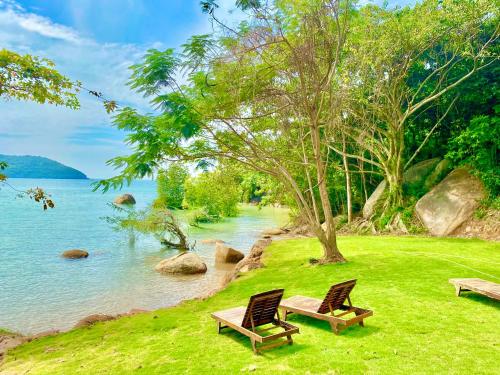 two chairs sitting on the grass near a body of water at Kalulushi Bungalows in Haad Pleayleam
