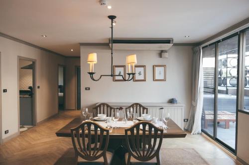 a dining room with a table with chairs and a chandelier at THEA Private Suites by TH District in Bangkok
