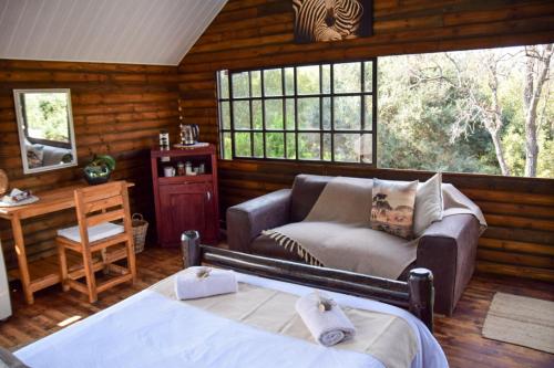 a living room with a couch and a bed in a cabin at Khululeka Guest Farm in Millvale