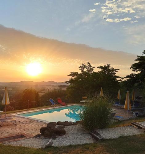 a swimming pool with the sunset in the background at Agriturismo Alla Vecchia Quercia in Pergola