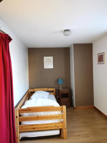 a bedroom with a wooden bed and a red curtain at Gîtes Les Grandes Voies - Clé Vacances in Le Ménil
