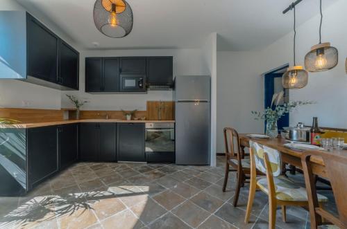 une cuisine avec des armoires noires et une table avec des chaises dans l'établissement Le Bel Endroit - Joli Studio vue jardin, à Bidache
