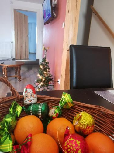 a basket of oranges on a table with a christmas tree at Gîtes Les Grandes Voies - Clé Vacances in Le Ménil