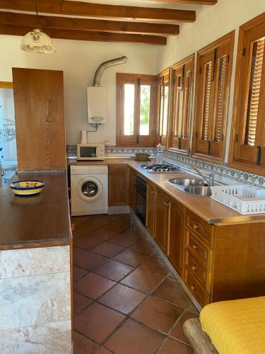 a large kitchen with wooden cabinets and a sink at Casa El Higueral in Mecina Alfahar