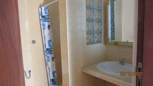 a bathroom with a sink and a shower with a mirror at Casa Branca in Porto Novo