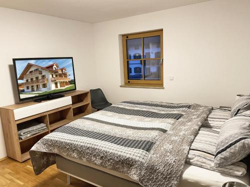 Schlafzimmer mit einem Bett und einem Flachbild-TV in der Unterkunft Ferienwohnungen Thum in Rosenheim