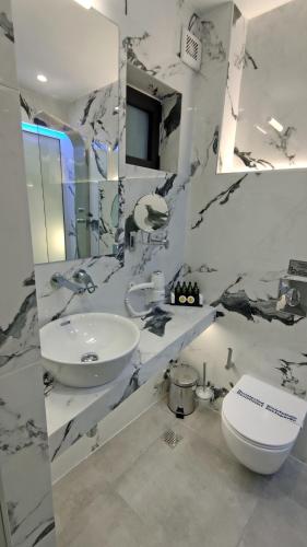 a white bathroom with a sink and a toilet at Anastasia Boutique Suites -Adults only & kids 12 plus in Asprovalta