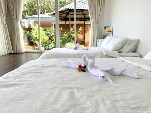 a large white bed with white sheets and flowers on it at Huyen's Home in Ba Ria
