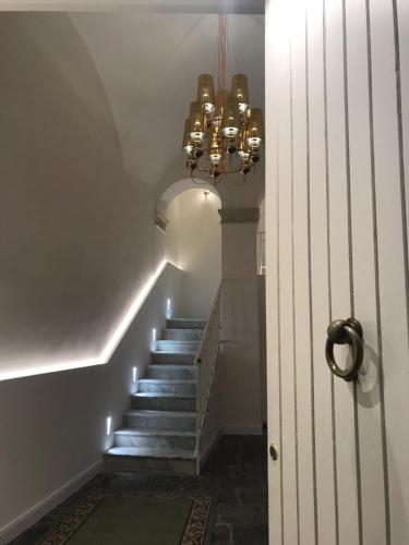 pasillo con escalera y lámpara de araña en Motta Palace Apartments & Rooms, en Motta SantʼAnastasia