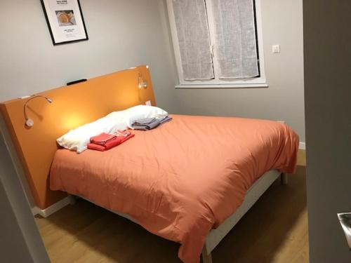1 dormitorio con cama con sábanas de color naranja y ventana en Maison de 4 chambres avec terrasse et wifi a Volvic en Volvic