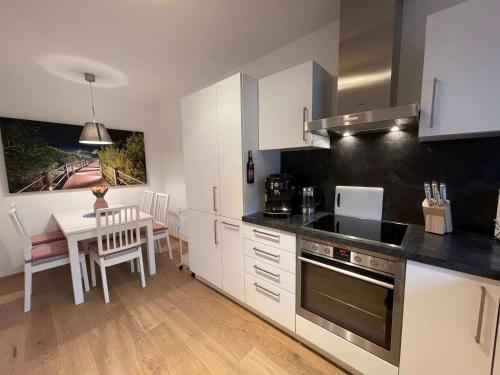 a kitchen with white cabinets and a table and a dining room at Ferienwohnung OutletCity in Metzingen