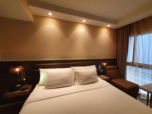 a bedroom with a bed and a chair and a window at Amora NeoLuxe Suites Hotel in Bangkok