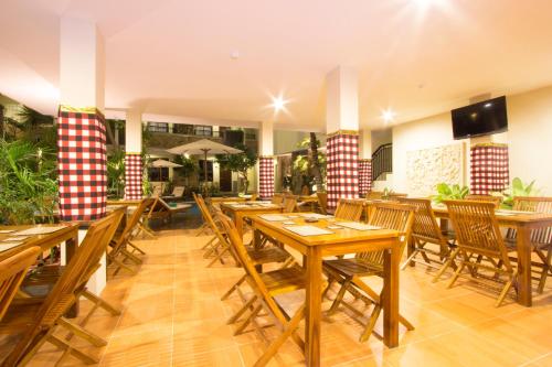 a restaurant with wooden tables and wooden chairs at Manggar Indonesia Hotel in Kuta