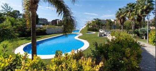 a swimming pool in a resort with palm trees at Paradise Village Port Aventuras in Salou