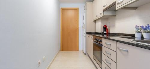 a kitchen with white cabinets and a counter top at Paradise Village Port Aventuras in Salou
