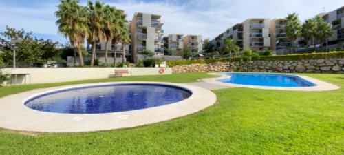 a large swimming pool in a grassy yard with buildings at Paradise Village Port Aventuras in Salou