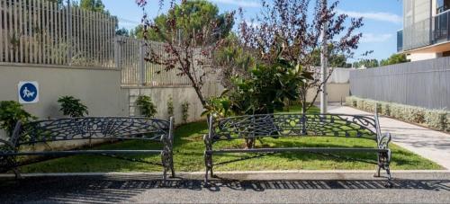 two metal benches sitting on the side of a sidewalk at Paradise Village Port Aventuras in Salou