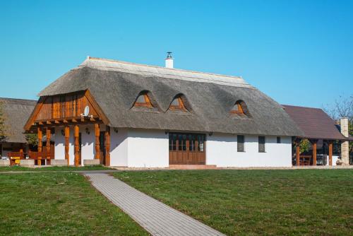 a large white building with a thatched roof at Csodaszarvas Vendégházak in Rábahidvég