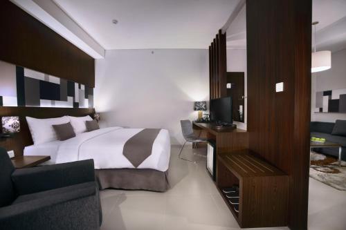 a bedroom with a bed and a desk with a television at Neo Denpasar by ASTON in Denpasar