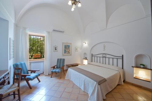a bedroom with a bed and two chairs and a table at Villa Aristide Amalfi Coast - POOL in Praiano