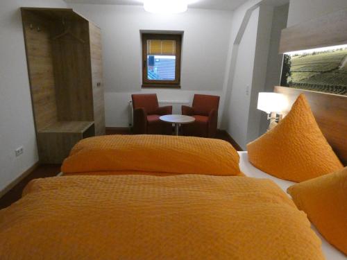 two beds in a hotel room with orange sheets at Gasthof zum Engel in Dottingen
