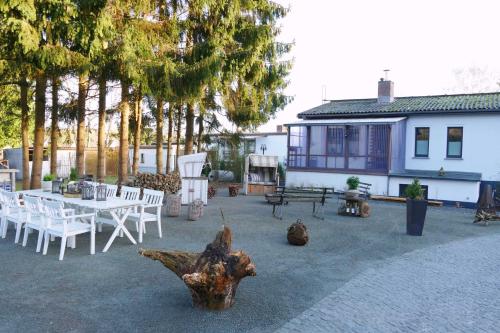 een patio met witte tafels, stoelen en bomen bij Ferienhaus Pier 1 in Ahlbeck