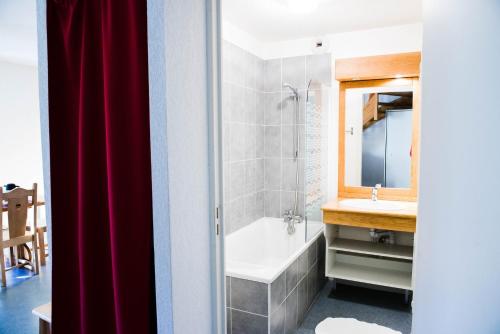 a bathroom with a tub and a sink and a mirror at Résidence Plein Soleil in Avrieux