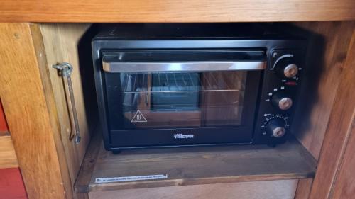 a black toaster oven in a wooden cabinet at AirstreamNB in Schayk