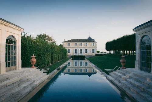 une maison avec une piscine d'eau en face de celle-ci dans l'établissement Château du Tertre, à Arsac