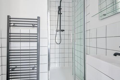 y baño con ducha y azulejos blancos. en Stylish 5 Bedroom 5 Bathroom House (Sleeps 10) with Garden, Smart TV and Free Parking by Yoko Property en Coventry