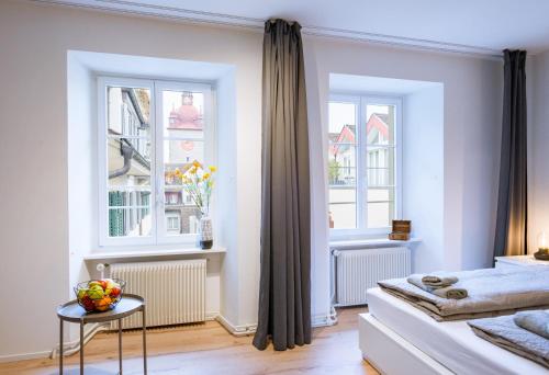 a bedroom with two windows and a bed and a table at HITrental Zur Metzgern Apartments in Luzern