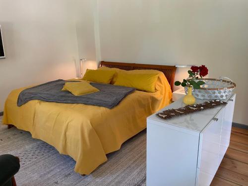 Un dormitorio con una cama con sábanas amarillas y una mesa. en Ferienwohnung an der Stadtvilla Rheinsberg, en Rheinsberg