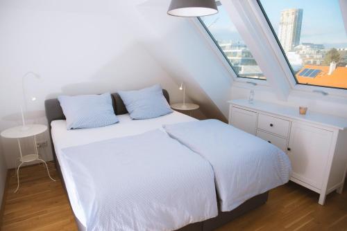 a bedroom with a white bed and a large window at Flair Appartement Alte Donau in Vienna
