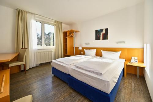ein Schlafzimmer mit einem großen Bett und einem Schreibtisch in der Unterkunft HESSE HOTEL Celle in Celle
