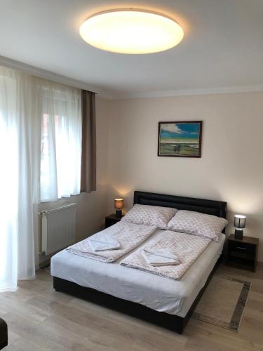 a bedroom with a bed and a large window at Oli Apartman in Hajdúszoboszló
