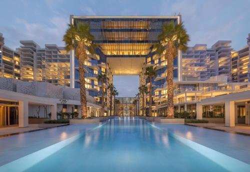 un grand bâtiment avec une piscine bordée de palmiers dans l'établissement FIVE Palm Jumeirah Resort - 2 Bedrooms plus Maids and Private Jacuzzi - ModernLux, à Dubaï