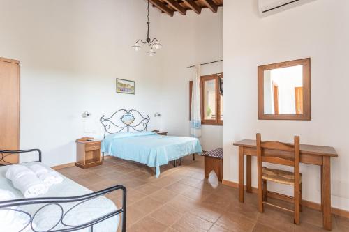 a bedroom with a bed and a desk and a mirror at Agriturismo S'Incant'e Sinis in San Salvatore