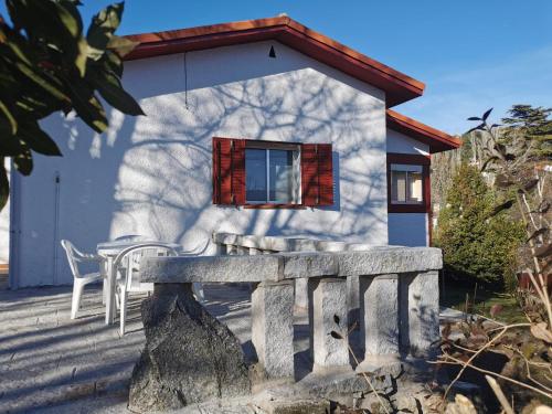 uma pequena casa com um banco à frente em Casita independiente con jardín y chimenea. em Cercedilla