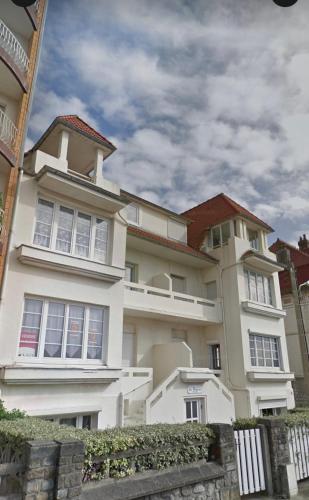 un grand bâtiment blanc avec une clôture devant lui dans l'établissement Bel appart 2/4 pers front de mer, à Le Touquet-Paris-Plage