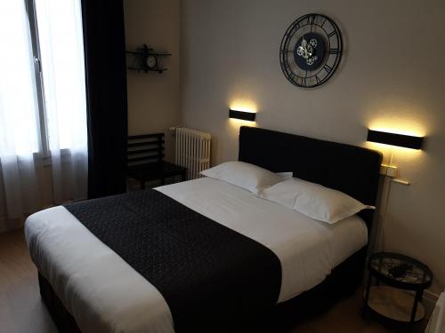 a bedroom with a large bed and a clock on the wall at Hotel Le Splendid in Troyes