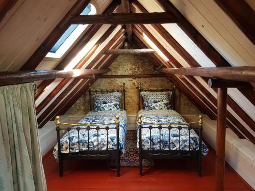 two beds in a attic bedroom with wooden ceilings at Âlde Bakhûs in Sondel